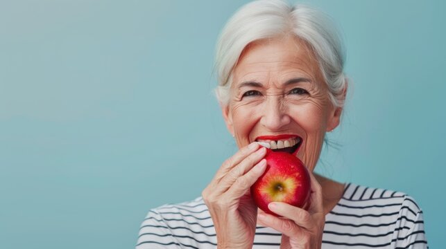 A senior female holding and eating a fresh ripe apple