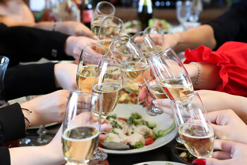 The girls make a toast with glasses of champagne at the festive table.