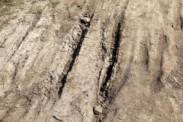 The dirt road is full of holes and ruts. The ground is dry and dusty. The road appears to be worn down and in need of repair