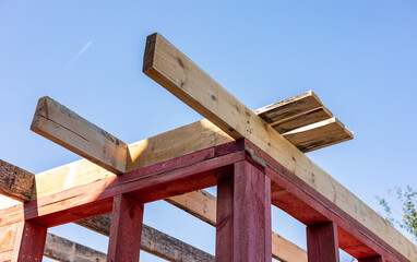 The image shows a close-up view of the wooden beams of a roof structure under construction. The image conveys a sense of progress and anticipation, suggesting that the house is nearing completion.