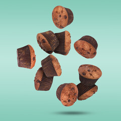 Delicious chocolate muffins falling on turquoise background
