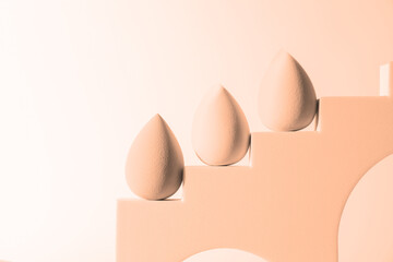 Stylish presentation of makeup sponges on white background, toned in peach fuzz color