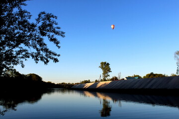  A hot air balloon with a basket flies in the evening sky.