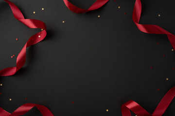 A stylish composition featuring a red ribbon and scattered star confetti on a smooth black background, perfect for festive occasions and celebrations