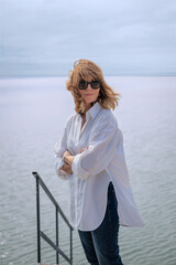Fototapeta premium Portrait of a blond haired woman standing by the lake