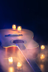 Acoustic guitar on a black background with candles.