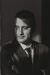 Obraz premium A man in a suit and tie is standing in front of a wall. He is looking at the camera with a serious expression
