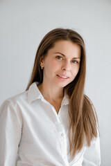 Young smiling confident business woman wearing white top shirt casual clothes looking camera isolated on grey background studio portrait. Vertical shot. Lifestyle concept. A professional in his field
