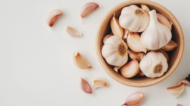 A close-up view of garlic cloves in a bowl, against a plain white background.