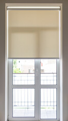 Roller blind beige color on a balcony door in old town apartment. Full height window with roller...
