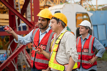 Asia engineer man worker use walkie talkie with team and spare crane background	