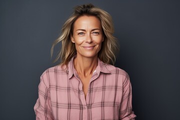Obraz premium Portrait of a blissful woman in her 40s dressed in a relaxed flannel shirt in blank studio backdrop