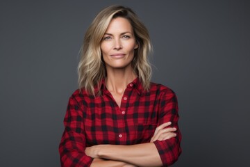 Obraz premium Portrait of a blissful woman in her 40s dressed in a relaxed flannel shirt in blank studio backdrop