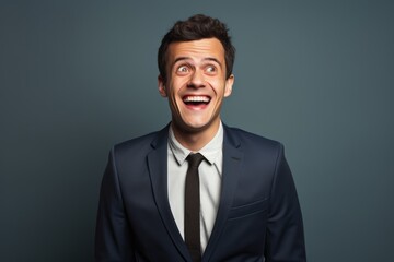 Portrait of a jovial man in his 20s wearing a professional suit jacket in blank studio backdrop