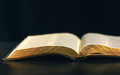 Open Bible on a black background. Religion concept.