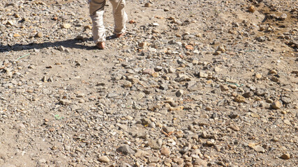Cropped shot of a man's feet without shoes walking on rocky ground