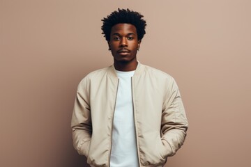 Obraz premium Portrait of a satisfied afro-american man in his 20s wearing a trendy bomber jacket on light wood minimalistic setup