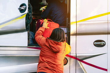 Tourists putting travel bag into travel bus at city street. Bus passengers putting luggage into the...