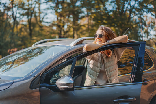 Happy woman driver traveling by car in forest enjoying freedom and nature