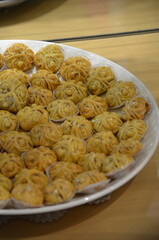 Plate of intricately designed traditional Moroccan pastries glazed with honey, presented on individual paper cups for serving
