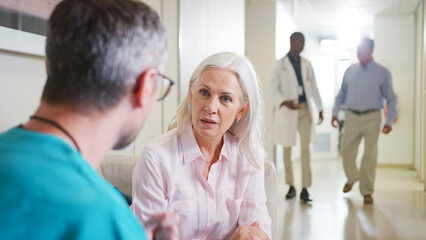 Obraz premium Doctor Having Serious Conversation With Mature Woman In Hospital Corridor