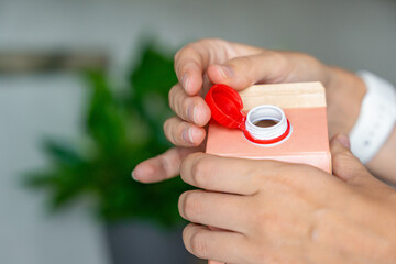 Long-life cardboard container from recycling materials with stationary plastic cap. Cap remains attached after opening, making the entire package easier to collect and recycle