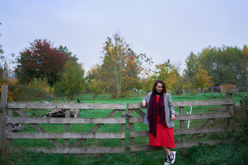 30-year-old medium-sized woman in a red muslin dress in an autumn garden