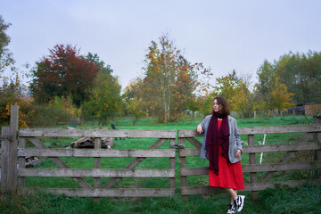 30-year-old medium-sized woman in a red muslin dress in an autumn garden