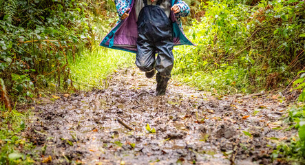 Child in welly boots, jump, jumping in mud.