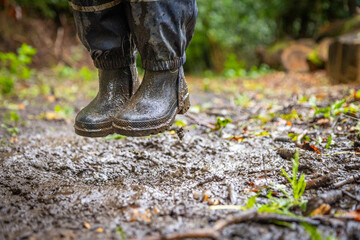 Child in welly boots, jump, jumping in mud.