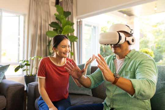 Using VR headset, father interacting while daughter smiling in living room