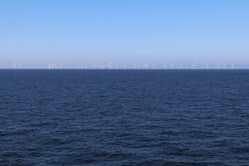 row of off shore wind mills at the north sea producing renewable energy
