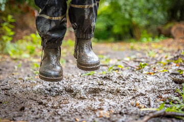 Child in welly boots, jump, jumping in mud.