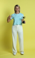 Happy winner with golden trophy cup on yellow background