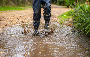 Child in welly boots, jump, jumping in mud.