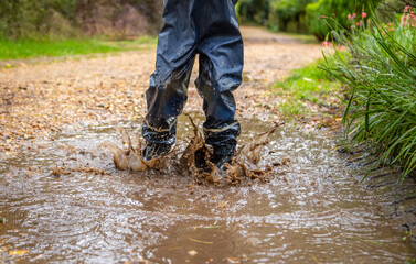 Child in welly boots, jump, jumping in mud.