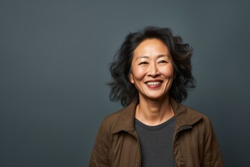 Obraz premium Portrait of a cheerful asian woman in her 50s sporting a long-sleeved thermal undershirt on plain cyclorama studio wall