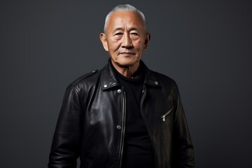 Obraz premium Portrait of a tender asian man in his 80s sporting a classic leather jacket on plain cyclorama studio wall