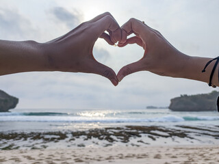 The couple shows their hands forming a heart symbolizing love and romance. Happy couple on the...