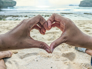 The couple shows their hands forming a heart symbolizing love and romance. Happy couple on the...