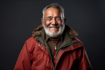 Obraz premium Portrait of a grinning indian man in his 70s wearing a warm parka on plain cyclorama studio wall