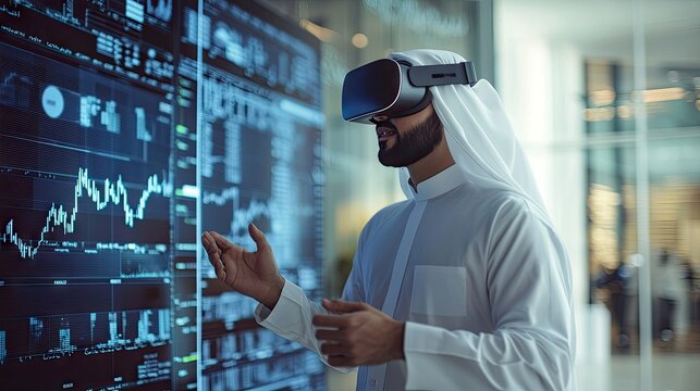 An Emirati man wearing white thobe and a VR headset is interacting with a digital screen in an office space. Stock market charts are on the wall 