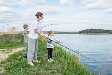 Mother and Children Fishing by River on Calm Day.
