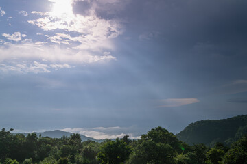A breathtaking panoramic view of a Taipei city skyline partially veiled by clouds. Golden sunbeams pierce through the overcast sky, casting a warm glow on the urban landscape. Taiwan.