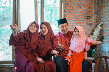 Asian Muslim family smiling showing hand gesture of presenting something with indoor background
