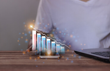 Young man with laptop hand using smartphone to visualize money growth The phone screen displays...