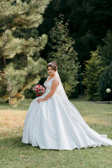 Fototapeta premium A woman in a white dress is standing in a field with a bouquet of flowers. She is wearing a veil and a white wedding dress