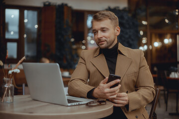 Young beard man using laptop on office, freelance work, outdoor close up hipster portrait, brutal, guy listening music on earphones, make photo and video, production, Bali, coffee cup, smartphone