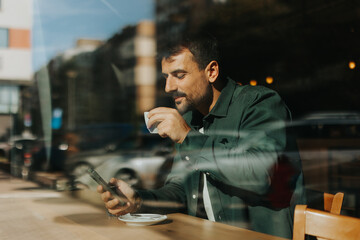 Toughtful man savoring coffee alone at a cozy cafe on a sunny day while lost in contemplation by the window