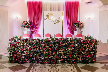 A table with a pink curtain and a beautiful arrangement of flowers on it. The table is set up for a special occasion, possibly a wedding or a formal event
